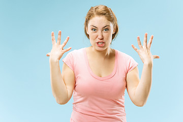 Image showing Beautiful female half-length portrait isolated on blue studio backgroud. The young emotional surprised woman