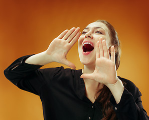 Image showing Isolated on orange young casual woman shouting at studio