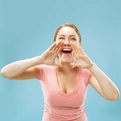 Image showing Isolated on blue young casual woman shouting at studio