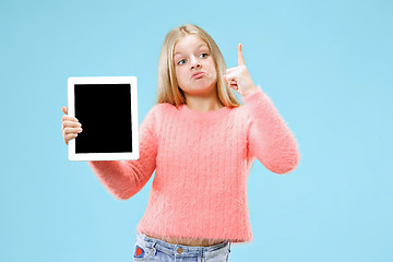 Image showing Little funny girl with tablet on blue background