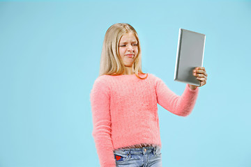 Image showing Teen girl with laptop. Love to computer concept. Attractive female half-length front portrait, trendy blue studio backgroud.