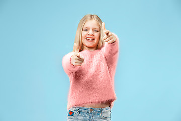 Image showing The happy teen girl standing and smiling against blue background.