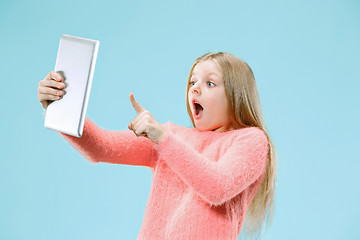 Image showing Teen girl with laptop. Love to computer concept. Attractive female half-length front portrait, trendy blue studio backgroud.