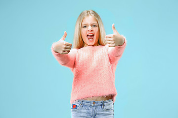 Image showing The happy teen girl standing and smiling against blue background.