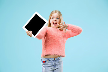 Image showing Little funny girl with tablet on blue background