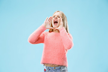 Image showing Isolated on blue young casual teen girl shouting at studio