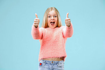 Image showing The happy teen girl standing and smiling against blue background.