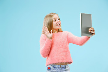 Image showing Teen girl with laptop. Love to computer concept. Attractive female half-length front portrait, trendy blue studio backgroud.
