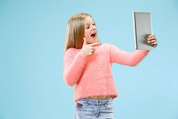 Image showing Teen girl with laptop. Love to computer concept. Attractive female half-length front portrait, trendy blue studio backgroud.