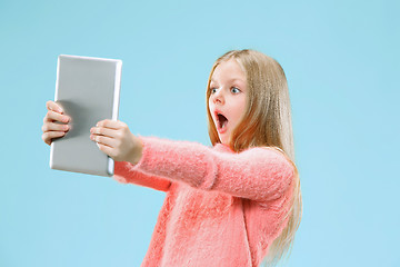 Image showing Teen girl with laptop. Love to computer concept. Attractive female half-length front portrait, trendy blue studio backgroud.