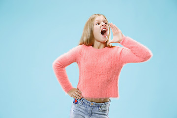 Image showing Isolated on blue young casual teen girl shouting at studio