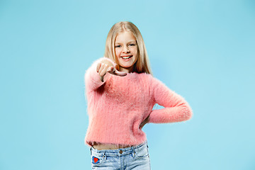 Image showing The happy teen girl pointing to you, half length closeup portrait on blue background.