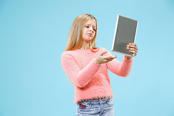 Image showing Teen girl with laptop. Love to computer concept. Attractive female half-length front portrait, trendy blue studio backgroud.