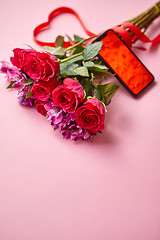 Image showing Pink roses bouquet with hart shaped bow and mobile phone with copy space screen