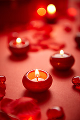 Image showing Romantic dinner decoration. Red candles, flower petals, on the table