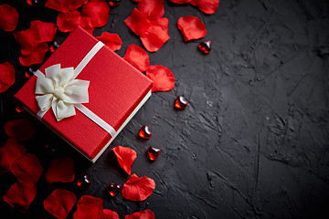 Image showing Gift box on black stone table. Romantic holiday background with rose petals