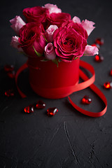 Image showing Pink roses bouquet packed in red box and placed on black stone background