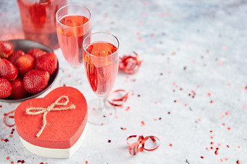 Image showing Bottle of rose champagne, glasses with fresh strawberries and heart shaped gift