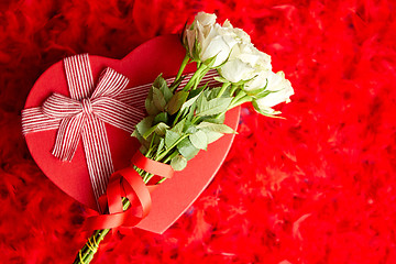 Image showing Heart shaped boxed gift, placed on red feathers background