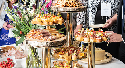 Image showing Businesspeople at banquet lunch break at business conference meeting. Assortment of canapes and finger food on the table.