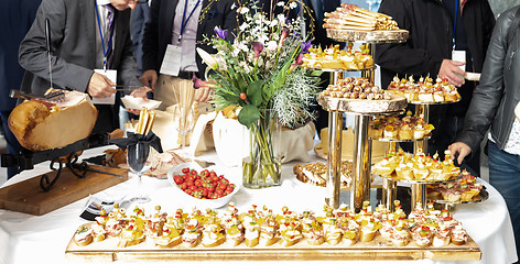 Image showing Businesspeople at banquet lunch break at business conference meeting. Assortment of canapes and finger food on the table.