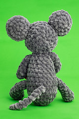 Image showing Grey knitted mouse with a heart in hand on a green background, rear view