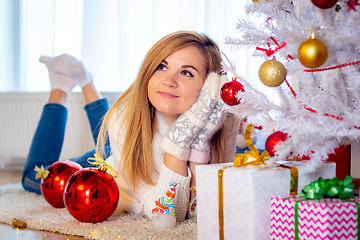 Image showing Girl dreams of a gift lying at the Christmas tree