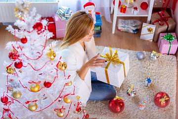 Image showing Girl opens New Year\'s gift at the Christmas tree