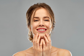 Image showing smiling young woman touching her face