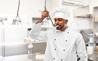 Image showing happy indian chef tasting food by ladle at kitchen