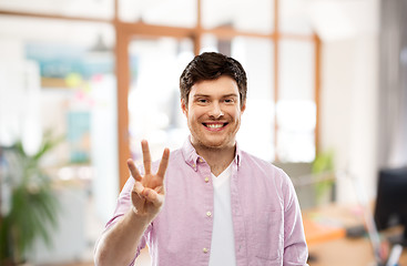 Image showing young man showing three fingers over office room