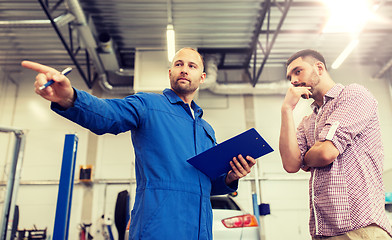 Image showing auto mechanic with clipboard and man at car shop