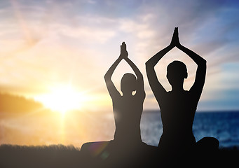 Image showing couple doing yoga in lotus pose over sunset