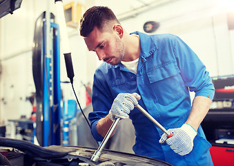 Image showing mechanic man with wrench repairing car at workshop