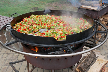 Image showing A lot of various sliced vegetables are fried in big steel pan