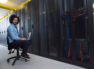 Image showing engineer working on a laptop in server room