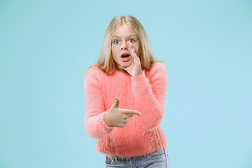 Image showing The young teen girl whispering a secret behind her hand over blue background