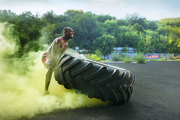 Image showing Handsome muscular man flipping big tire outdoor.