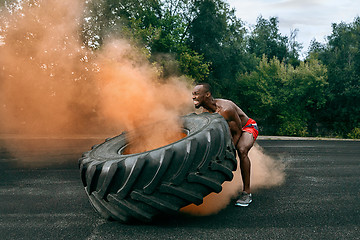 Image showing Handsome muscular man flipping big tire outdoor.