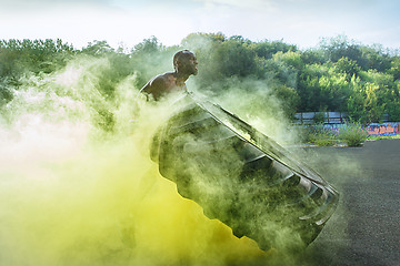 Image showing Handsome muscular man flipping big tire outdoor.