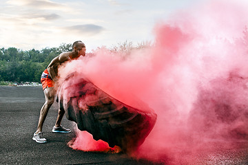 Image showing Handsome muscular man flipping big tire outdoor.