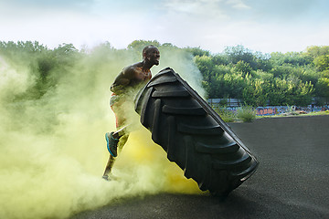 Image showing Handsome muscular man flipping big tire outdoor.