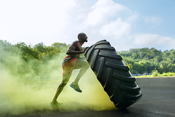 Image showing Handsome muscular man flipping big tire outdoor.