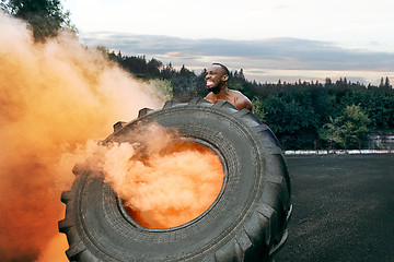 Image showing Handsome muscular man flipping big tire outdoor.