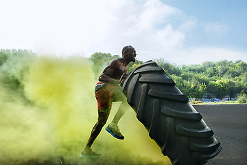 Image showing Handsome muscular man flipping big tire outdoor.