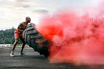 Image showing Handsome muscular man flipping big tire outdoor.