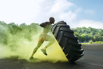 Image showing Handsome muscular man flipping big tire outdoor.