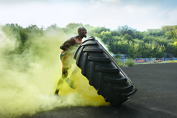 Image showing Handsome muscular man flipping big tire outdoor.