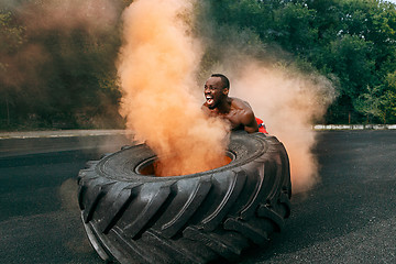 Image showing Handsome muscular man flipping big tire outdoor.