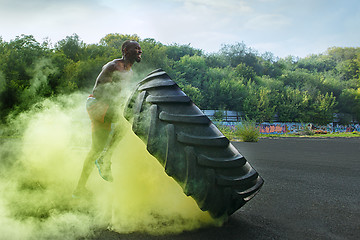 Image showing Handsome muscular man flipping big tire outdoor.